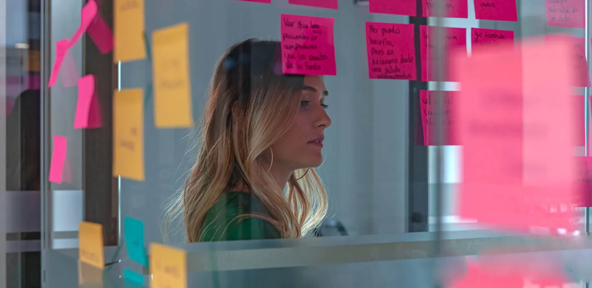 Female young woman looking at glass post-it adhesive notes.